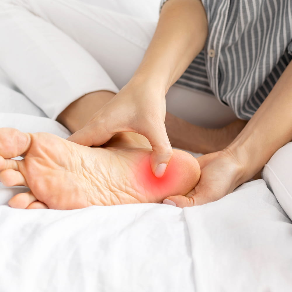 A woman holding her foot, which has plantar fasciitis